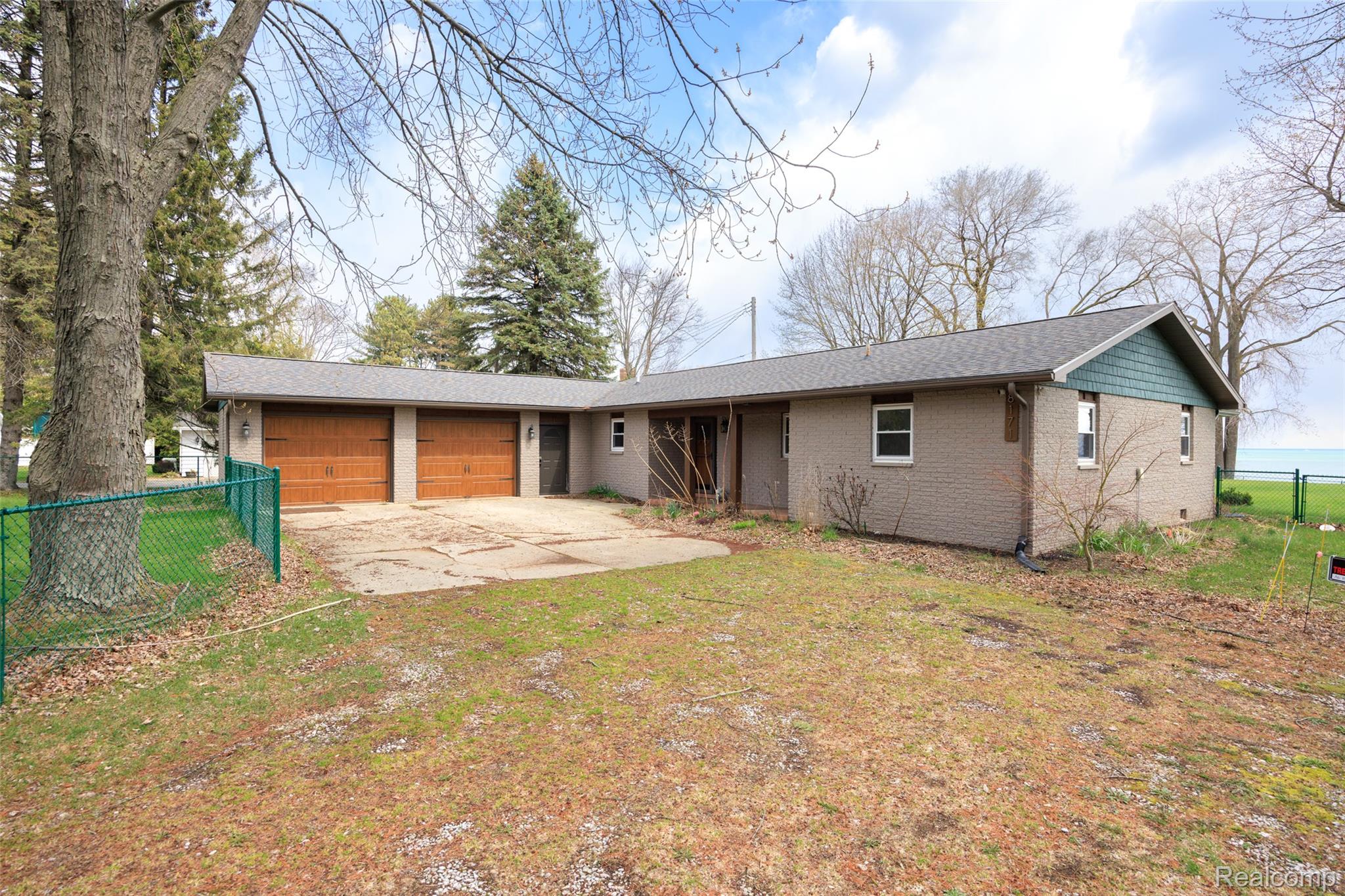 Ranch-style home with an attached garage, driveway, brick siding, and roof with shingles
