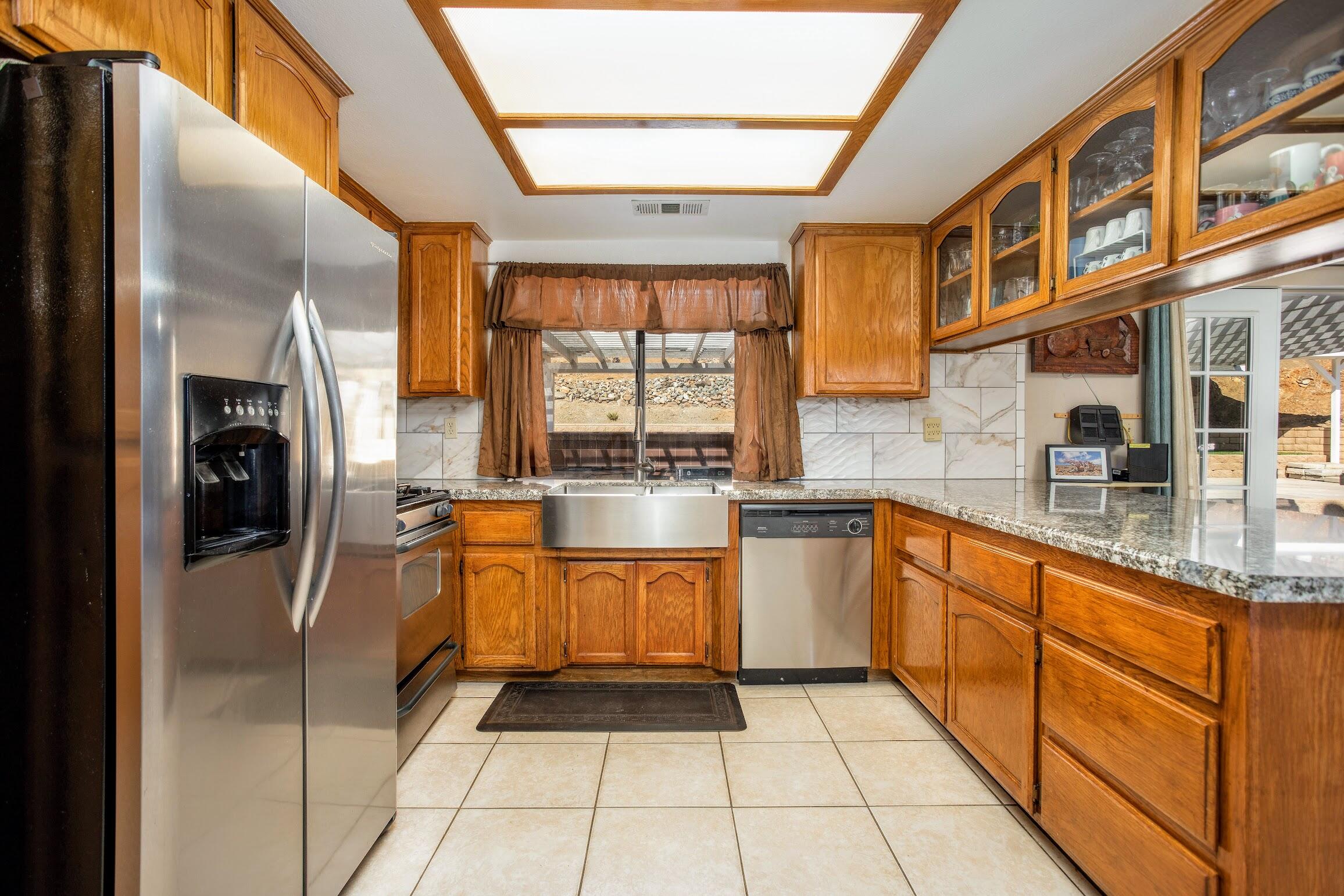 16276 Rancherias Road Apple Valley, CA 92307 - Photo 11 of 27 a large kitchen with stainless steel appliances granite countertop a stove a sink and a refrigerator