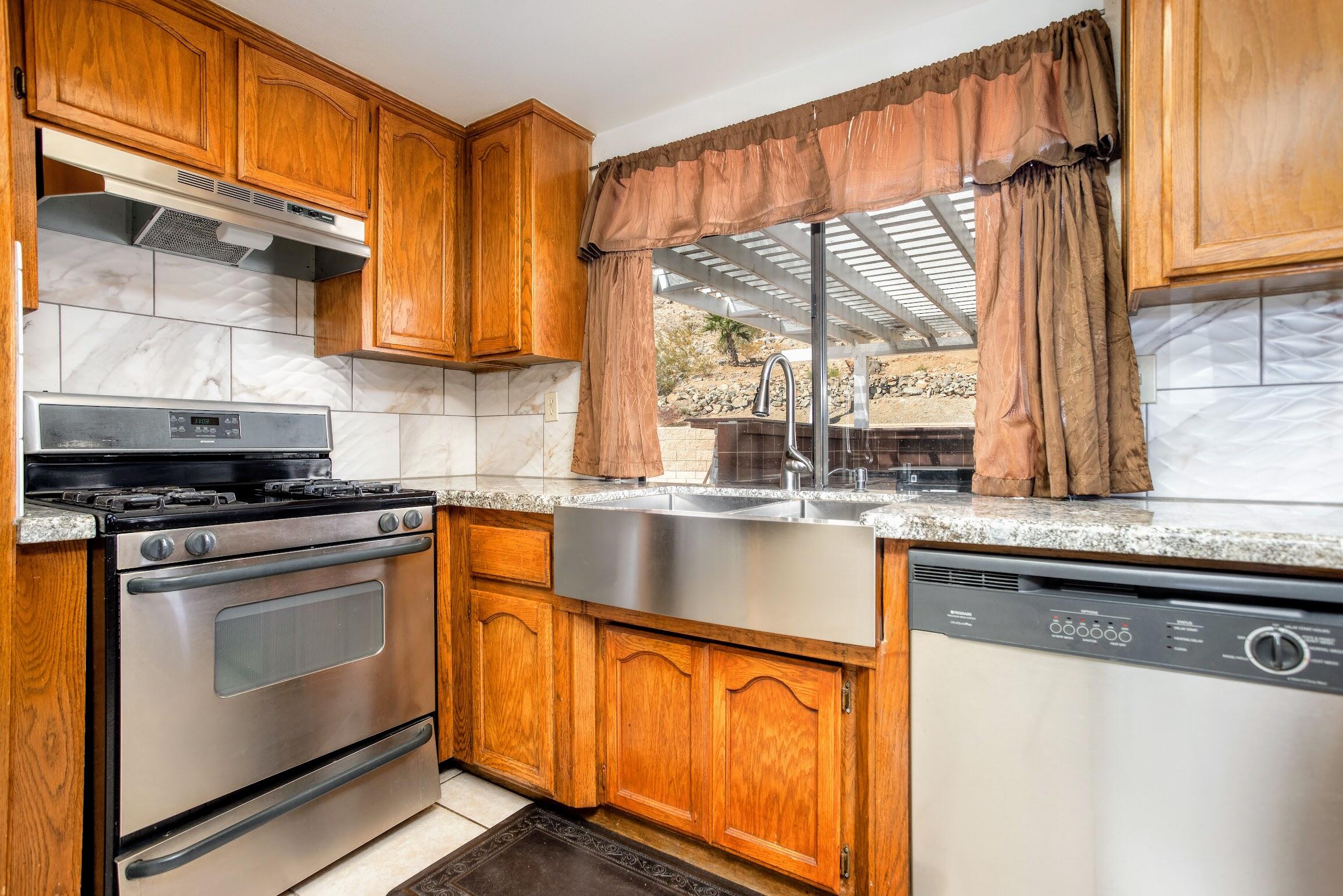 16276 Rancherias Road Apple Valley, CA 92307 - Photo 12 of 27 a kitchen with stainless steel appliances granite countertop a stove a sink and a microwave