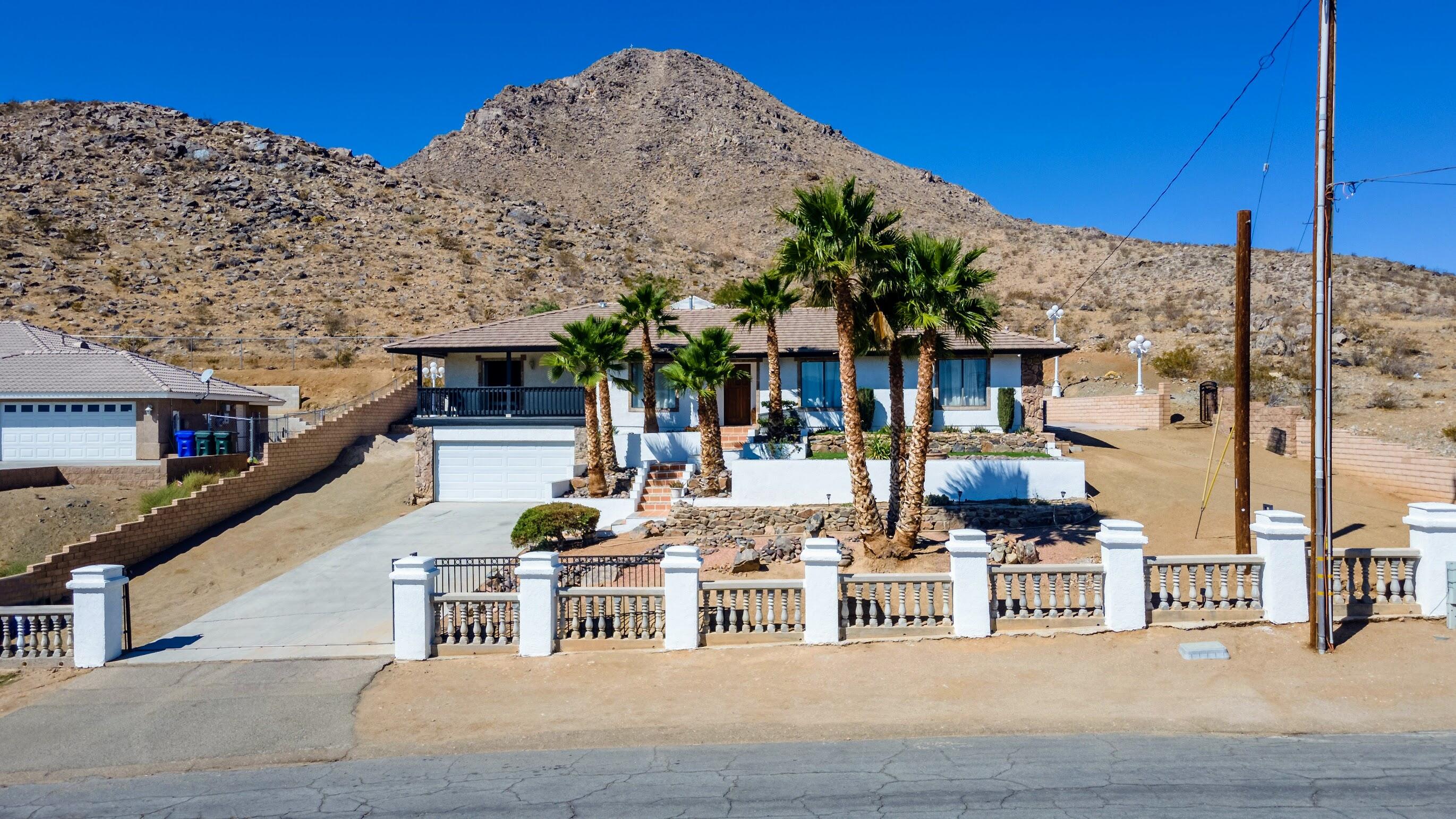 16276 Rancherias Road Apple Valley, CA 92307 - Photo 3 of 27 a view of a patio with couches table and chairs under an umbrella with a small yard