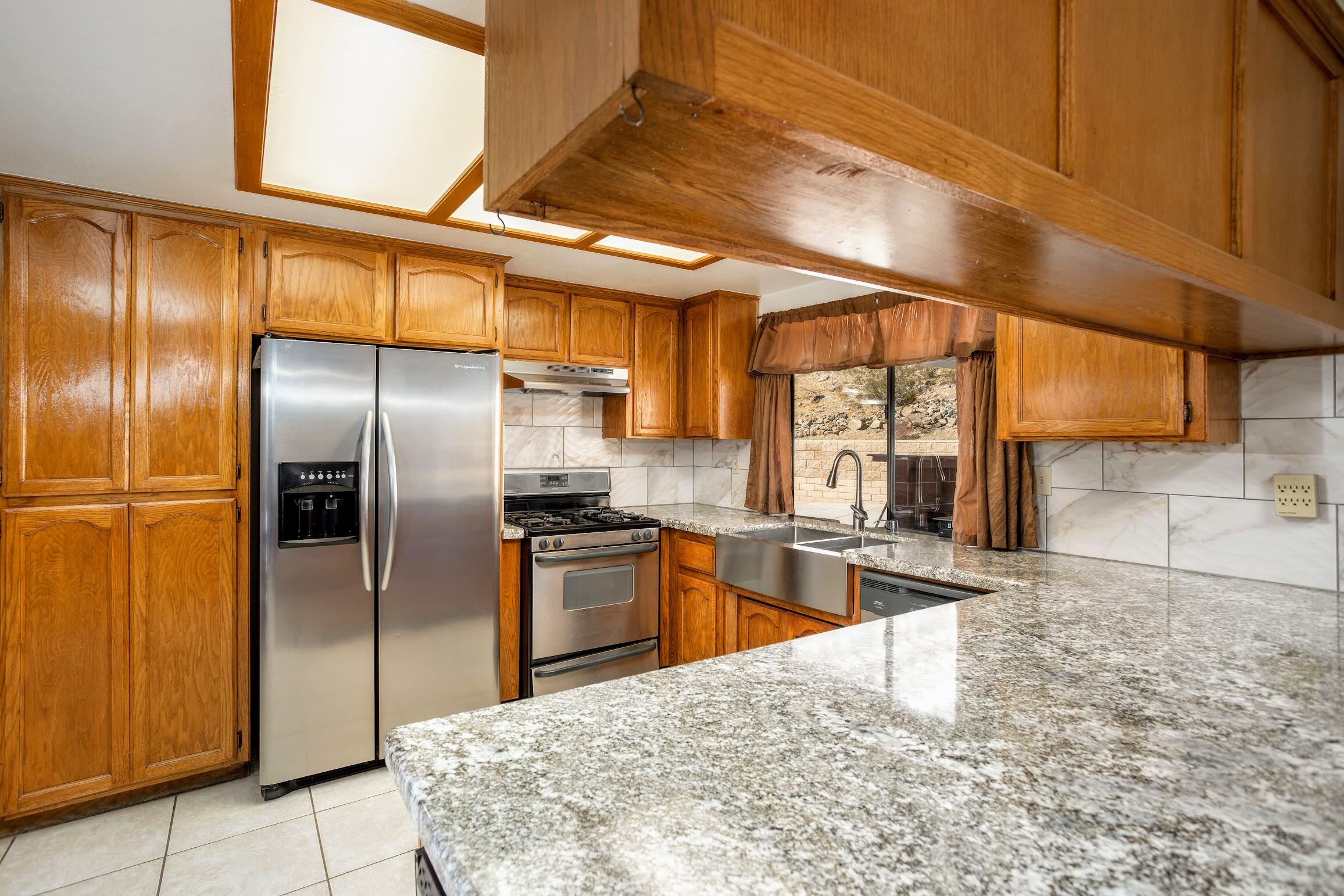 16276 Rancherias Road Apple Valley, CA 92307 - Photo 10 of 27 a kitchen with granite countertop a refrigerator and countertop cabinets