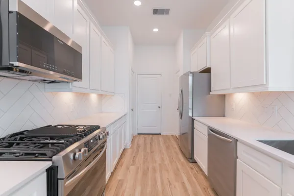 a large kitchen with stainless steel appliances a large counter top a stove and a sink