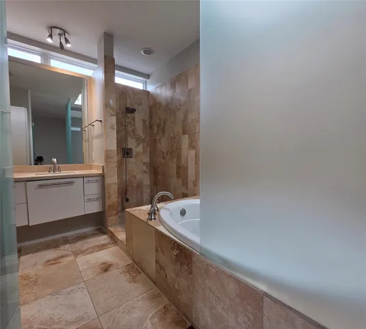 a bathroom with a granite countertop sink a bathtub and mirror
