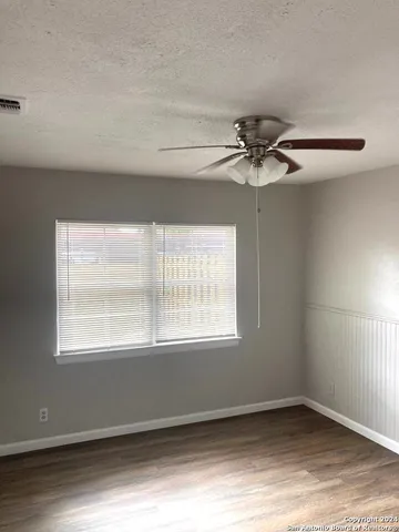 an empty room with a window and a fan
