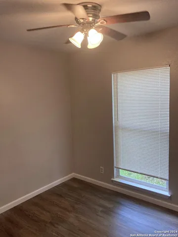 a view of a small space with wooden floor a chandelier fan and a window