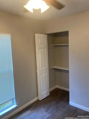 a view of an empty room with wooden floor and closet
