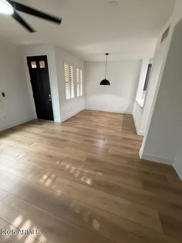 a view of an empty room with window and wooden floor