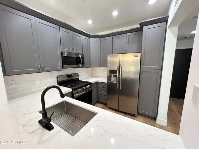 a kitchen with stainless steel appliances granite countertop a refrigerator and a sink
