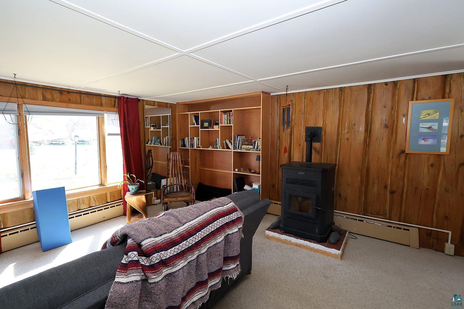 83185 Washington Avenue Port Wing, WI 54865 - Photo 13 of 26 Interior space featuring wood paneling, a built-in wood stove, and a wall of built-in shelving