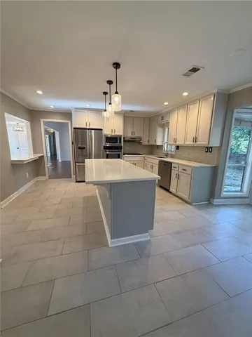 a large kitchen with kitchen island a sink a counter space and stainless steel appliances