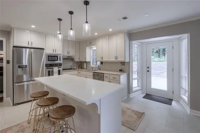 a kitchen with stainless steel appliances granite countertop a sink a stove a refrigerator cabinets and a dining table