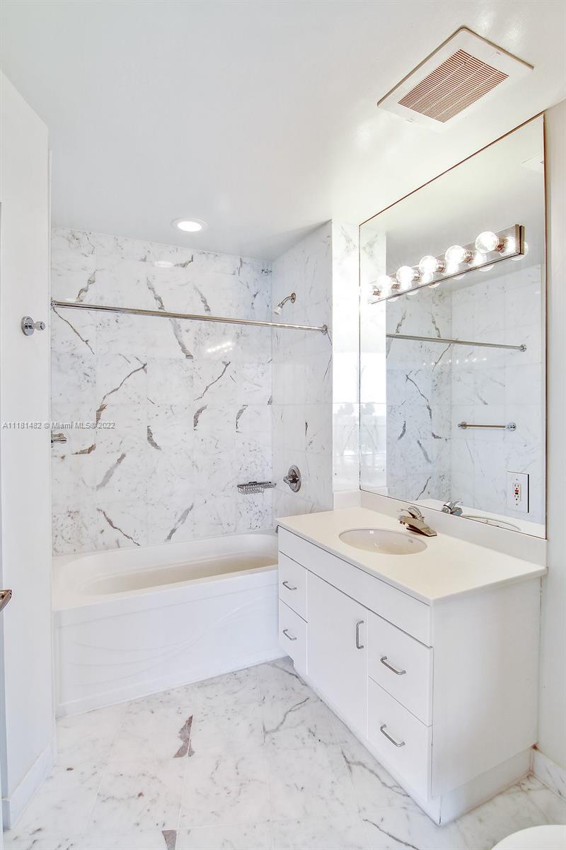 1500 Bay Road, Unit C2312 Miami Beach, FL 33139 - Photo 16 of 20 a spacious bathroom with a granite countertop sink a mirror and a bathtub