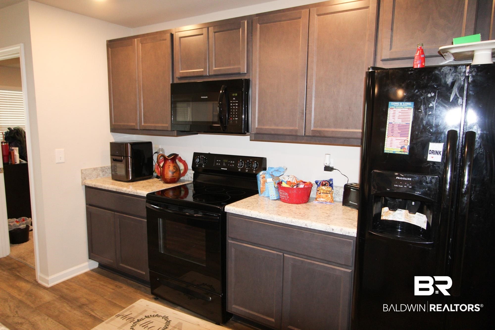 1502 Majesty Loop Foley, AL 36535 - Photo 7 of 26 Kitchen featuring dark brown cabinets, light hardwood / wood-style flooring, and black appliances