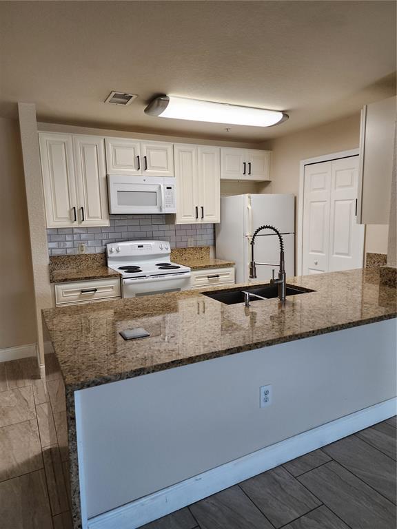 a kitchen with stainless steel appliances granite countertop a sink a stove and white cabinets