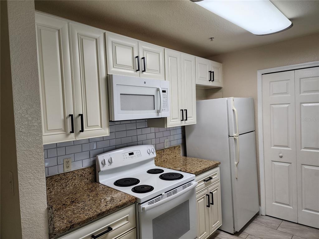 5455 Vineland Road, Unit 3105 Orlando, FL 32811 - Photo 2 of 11 a kitchen with white cabinets and white appliances
