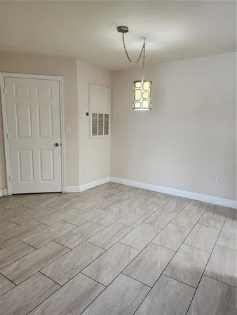 an empty room with kitchen chandelier and windows