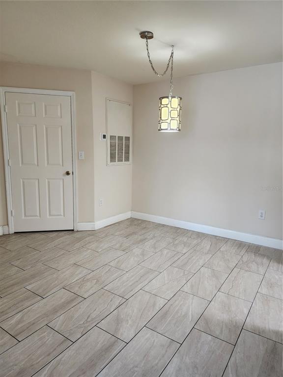 5455 Vineland Road, Unit 3105 Orlando, FL 32811 - Photo 6 of 11 an empty room with kitchen chandelier and windows