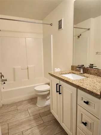 a bathroom with a granite countertop sink a toilet and shower
