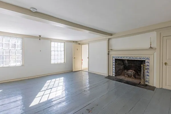 an empty room with wooden floor fireplace and windows