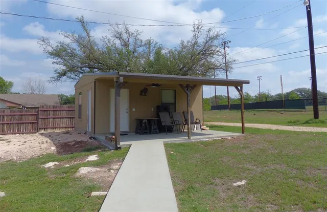 a view of a house that has a bunch of plants and large trees