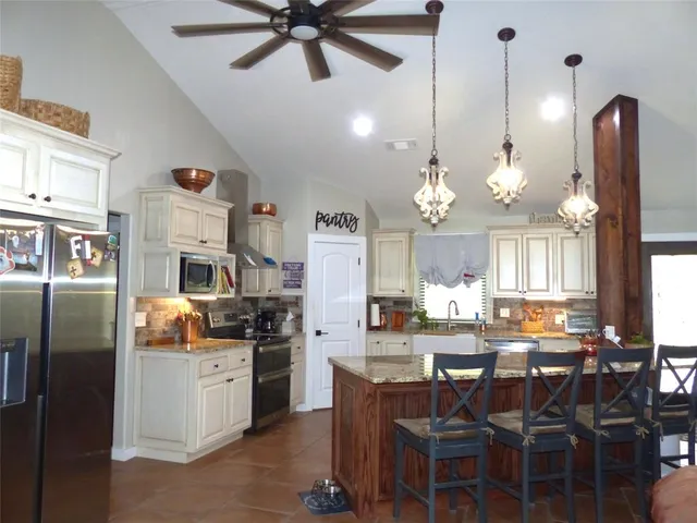 a kitchen with stainless steel appliances granite countertop a refrigerator a sink dishwasher a dining table and chairs with wooden floor