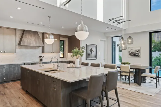 a kitchen with stainless steel appliances kitchen island granite countertop a table chairs sink and cabinets