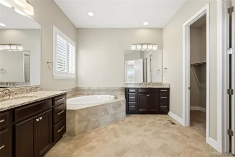 a spacious bathroom with a granite countertop tub sink shower and mirror