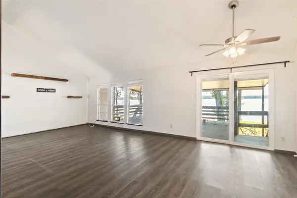 an empty room with wooden floor chandelier fan and windows
