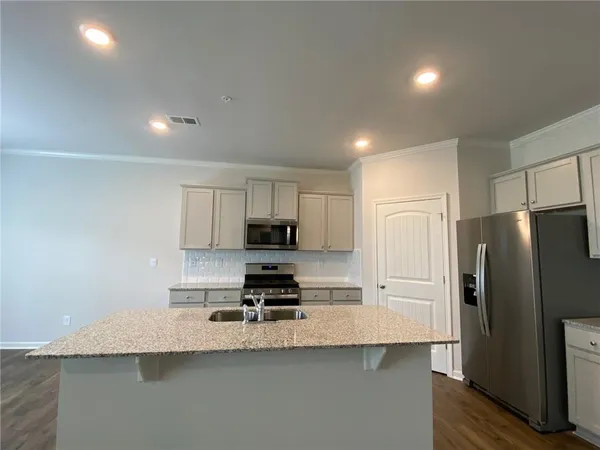 a kitchen with stainless steel appliances granite countertop a sink a refrigerator and a granite counter tops