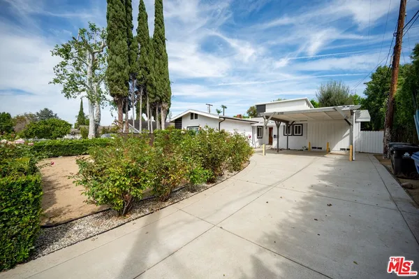 a view of a house with a yard and potted plants