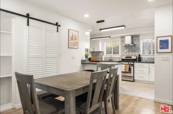 a kitchen with stainless steel appliances granite countertop a stove a refrigerator a kitchen island a stove a dining table and chairs