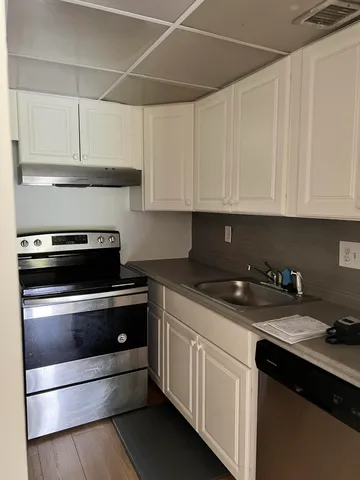 a kitchen with granite countertop white cabinets and stainless steel appliances