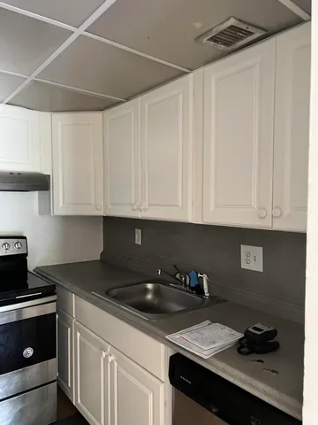 a kitchen with granite countertop white cabinets and black appliances