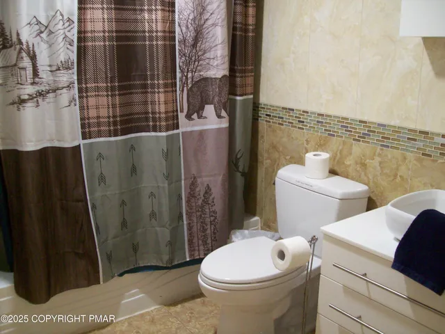 a white toilet sitting next to a bathroom sink and a shower