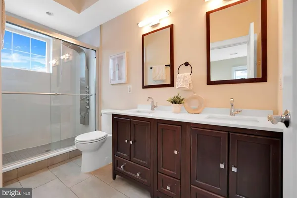 a bathroom with a double vanity sink toilet mirror and shower