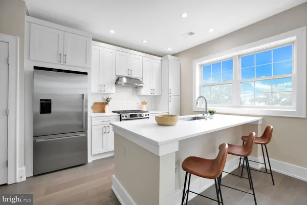 a kitchen with a sink a stove a refrigerator and white cabinets