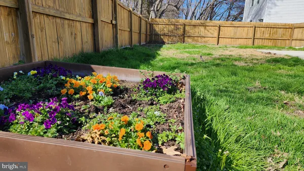 a view of a garden with flowers and wooden fence