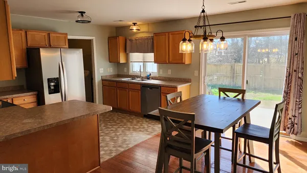 a kitchen with stainless steel appliances a dining table chairs and wooden floor
