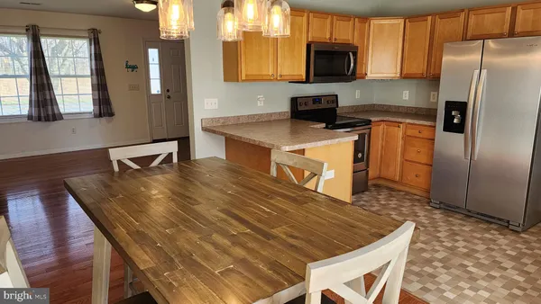 a kitchen with stainless steel appliances granite countertop a kitchen island a table and chairs in it