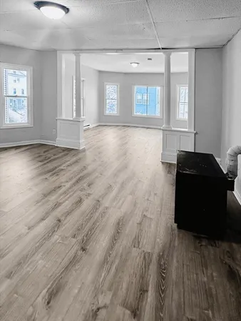 an empty room with wooden floor and windows