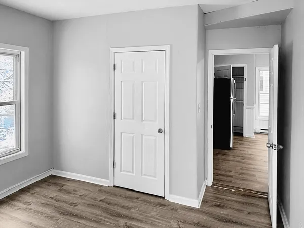an empty room with wooden floor closet and windows