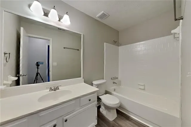 a bathroom with a toilet a sink a mirror a bathtub and vanity