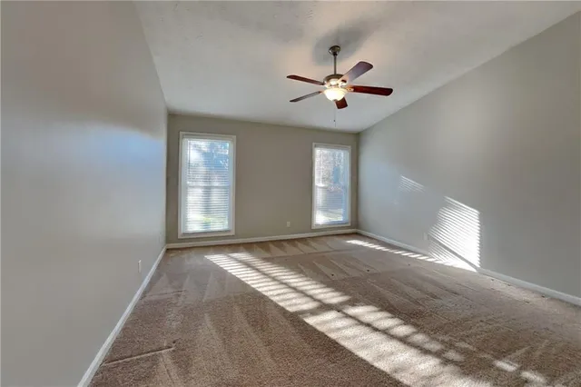 a view of an empty room with window and chandelier fan