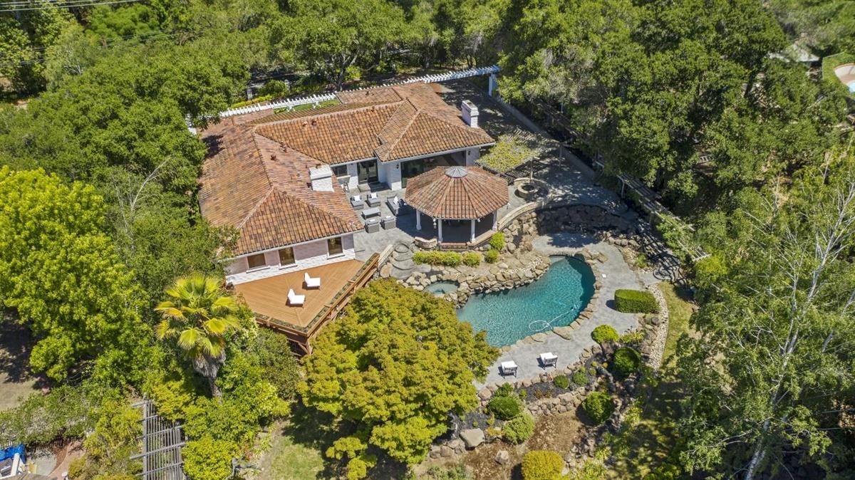 an aerial view of a house with swimming pool and large trees