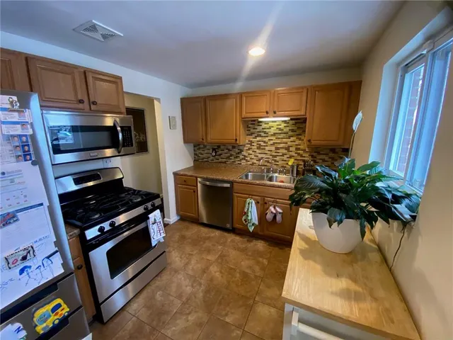 a kitchen with stainless steel appliances kitchen island granite countertop a stove a sink and a white cabinets