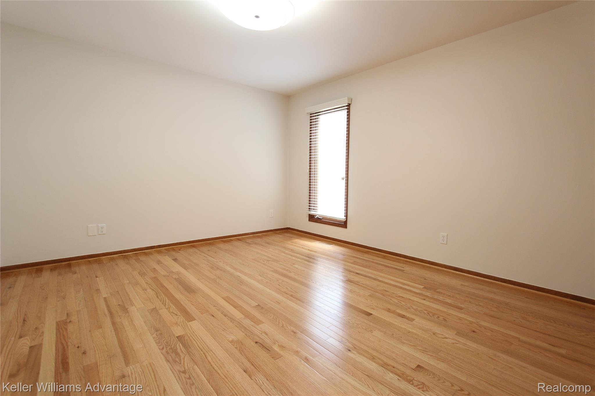 21850 River Ridge Trail Farmington, MI 48335 - Photo 7 of 33 Spacious room featuring wood-finish flooring, neutral wall tones, a single window with blinds, and a flush-mount ceiling light