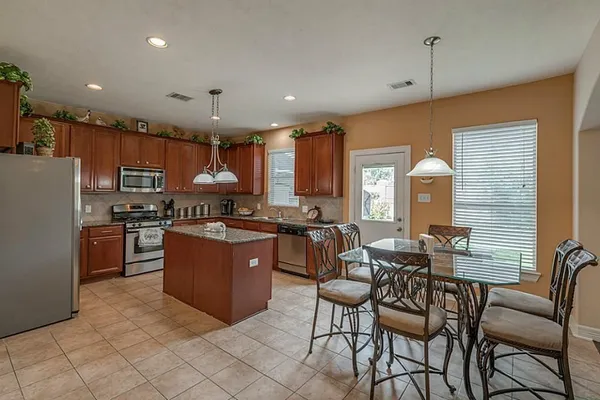 a kitchen with stainless steel appliances granite countertop a stove top oven a sink dishwasher a dining table and chairs with wooden floor