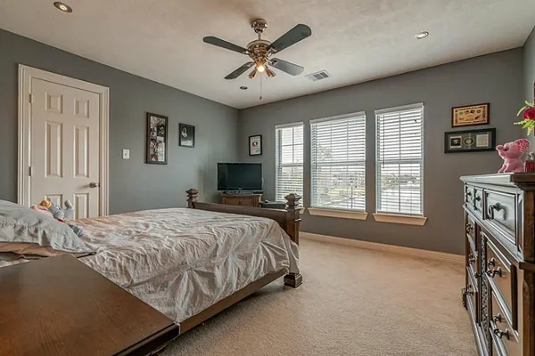 a bedroom with a large bed a flat screen tv and a large window