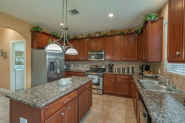 a kitchen with kitchen island granite countertop a sink a counter top space appliances and cabinets