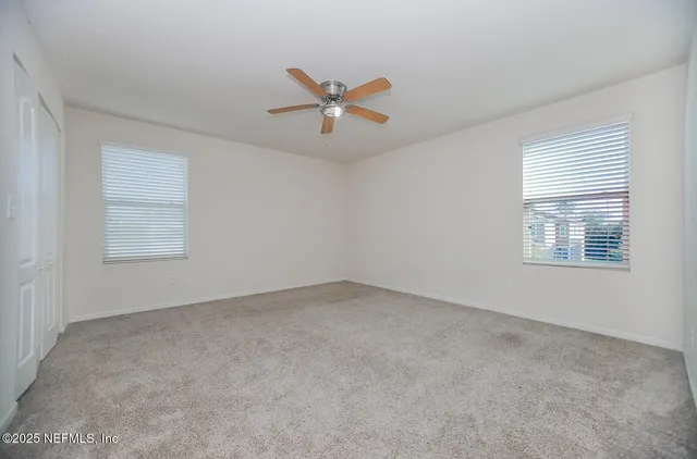 an empty room with windows and fan